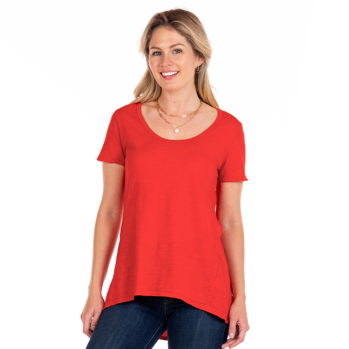 A woman with long blonde hair wearing the Fresh Produce Clothes Luna Top | Plus Size in red and blue jeans smiles while standing against a white background.