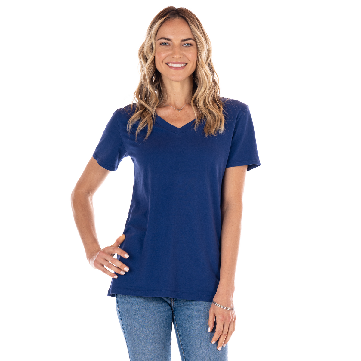 Smiling woman with long wavy hair wearing the Allure T Moonlight by Fresh Produce Clothes and blue jeans stands against a white background, with one hand on her hip.