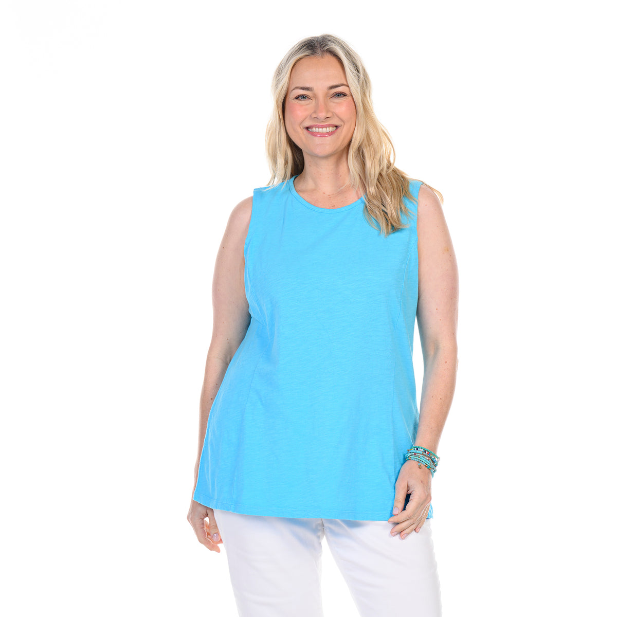Smiling woman with long blonde hair wearing a sleeveless light blue Chloe Tank by Fresh Produce Clothes (Plus Size, Clearance), featuring flattering princess seams and paired with white pants, standing against a plain white background—perfect for effortless layering.