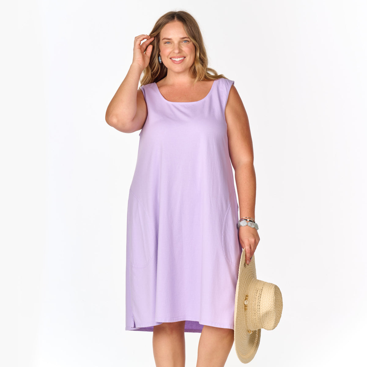 A woman wears a lavender scoop-neck La Jolla Dress | Plus Size | Clearance and holds a straw hat.