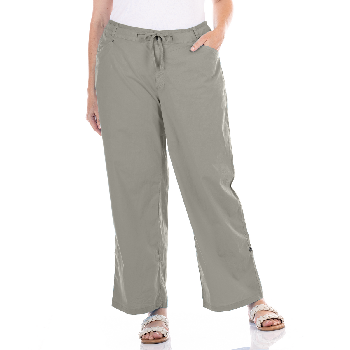 A person wearing the Fresh Produce Clothes Safari Rollup Pant in plus size, styled with a white top and sandals, stands against a white background with one hand in their pocket. The image displays only the lower half of their body.