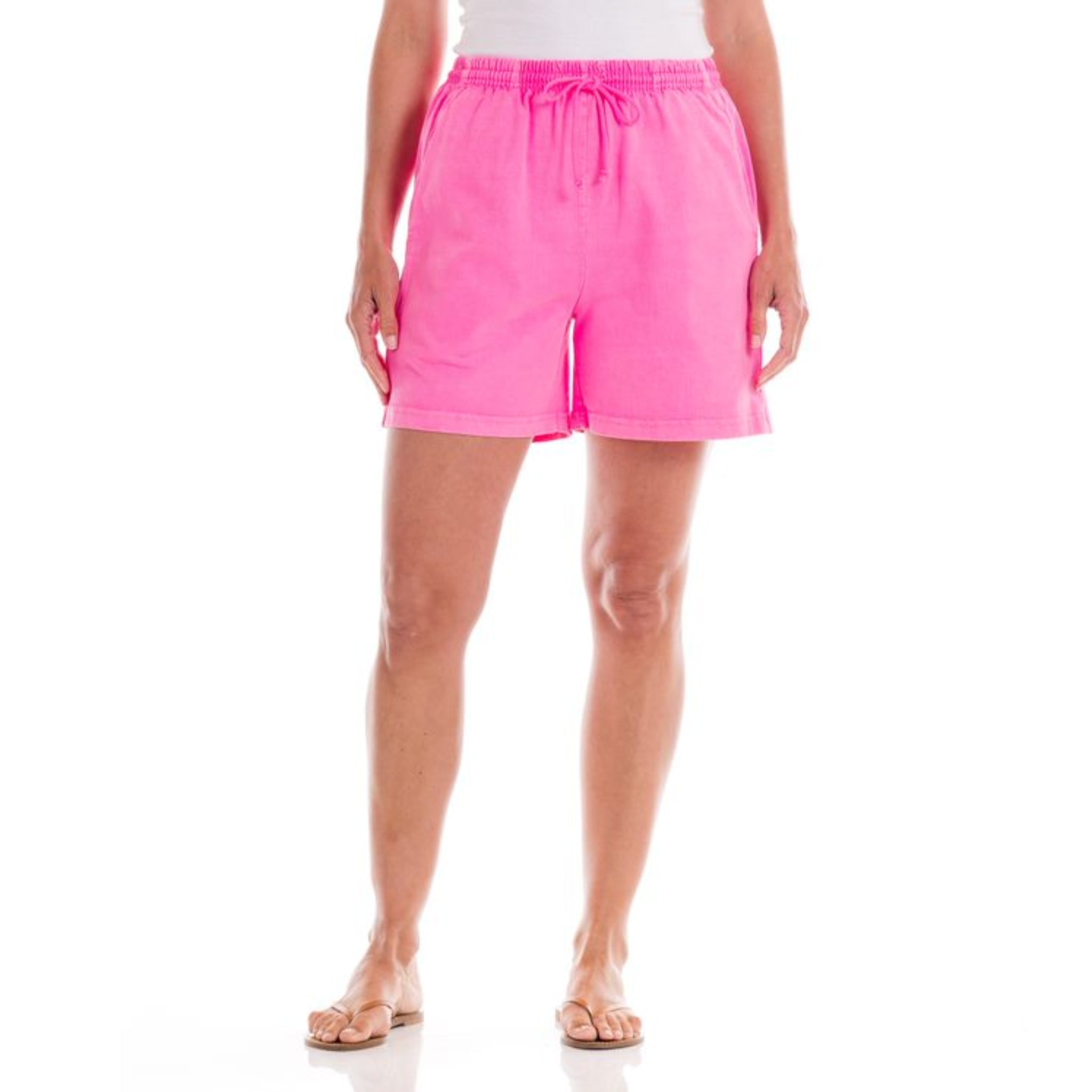 Wearing the Fresh Produce Clothes Jersey Shorts | Clearance in bright pink, a person stands facing forward against a white background. The image highlights the heavy cotton shorts, which feature a drawstring waist and deep side pockets, paired with flip-flops and focusing on the lower body.