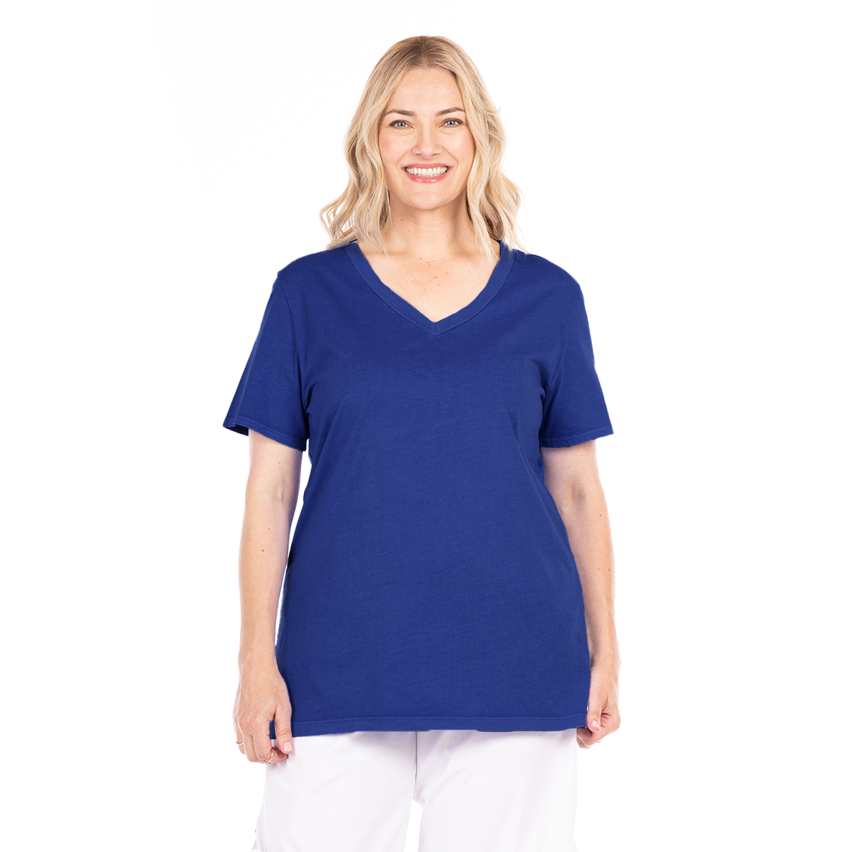 Certainly! Here’s a rewritten sentence incorporating the provided product data: A woman with blonde hair smiles as she stands against a plain white background, wearing the Fresh Produce Clothes Allure T Moonlight V-neck short sleeve shirt in Moonlight and white pants.