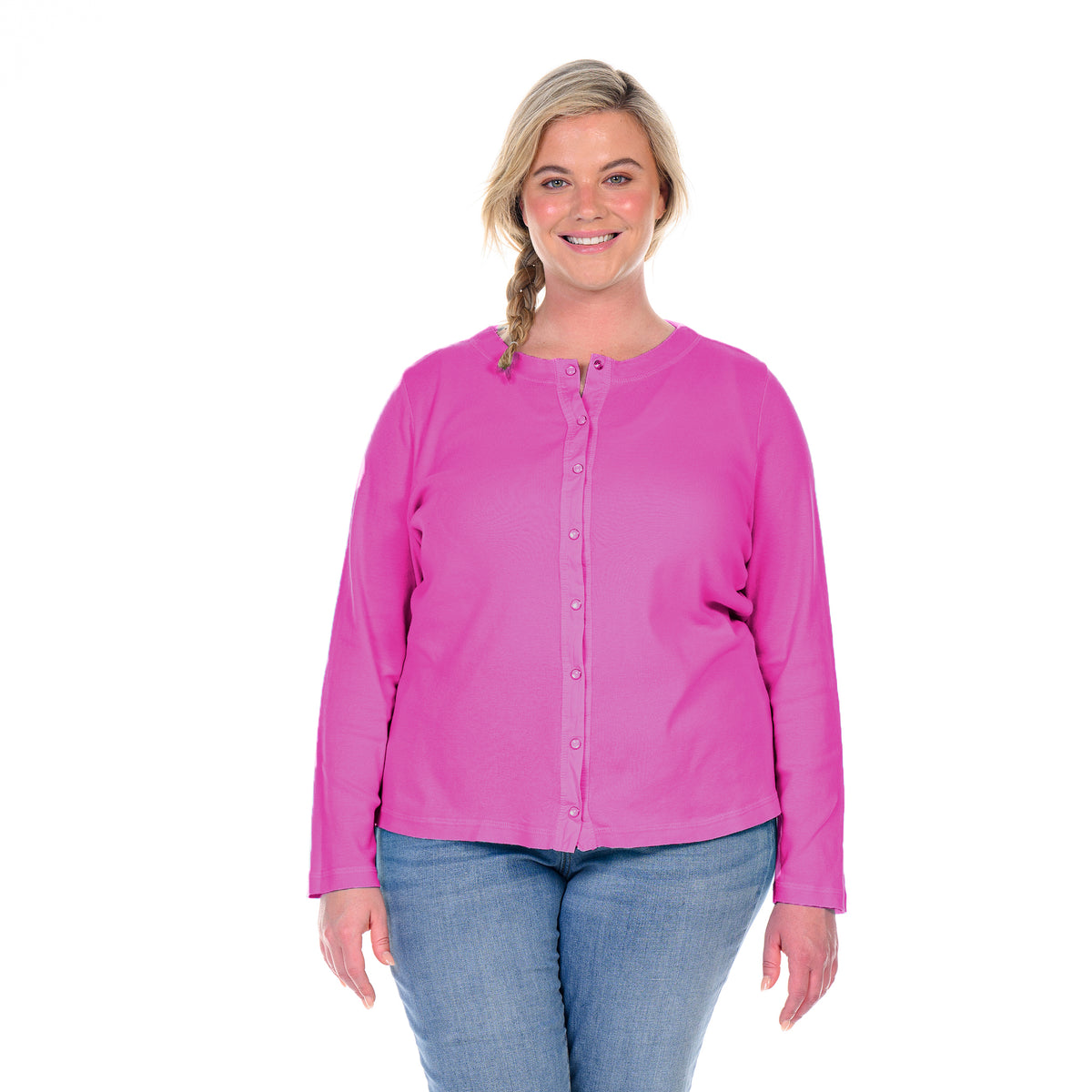 A smiling woman with blonde hair in a side braid stands against a white background, wearing the Fresh Produce Clothes Baby Rib Cardigan | Plus Size BFN CHB in bright pink with blue jeans.