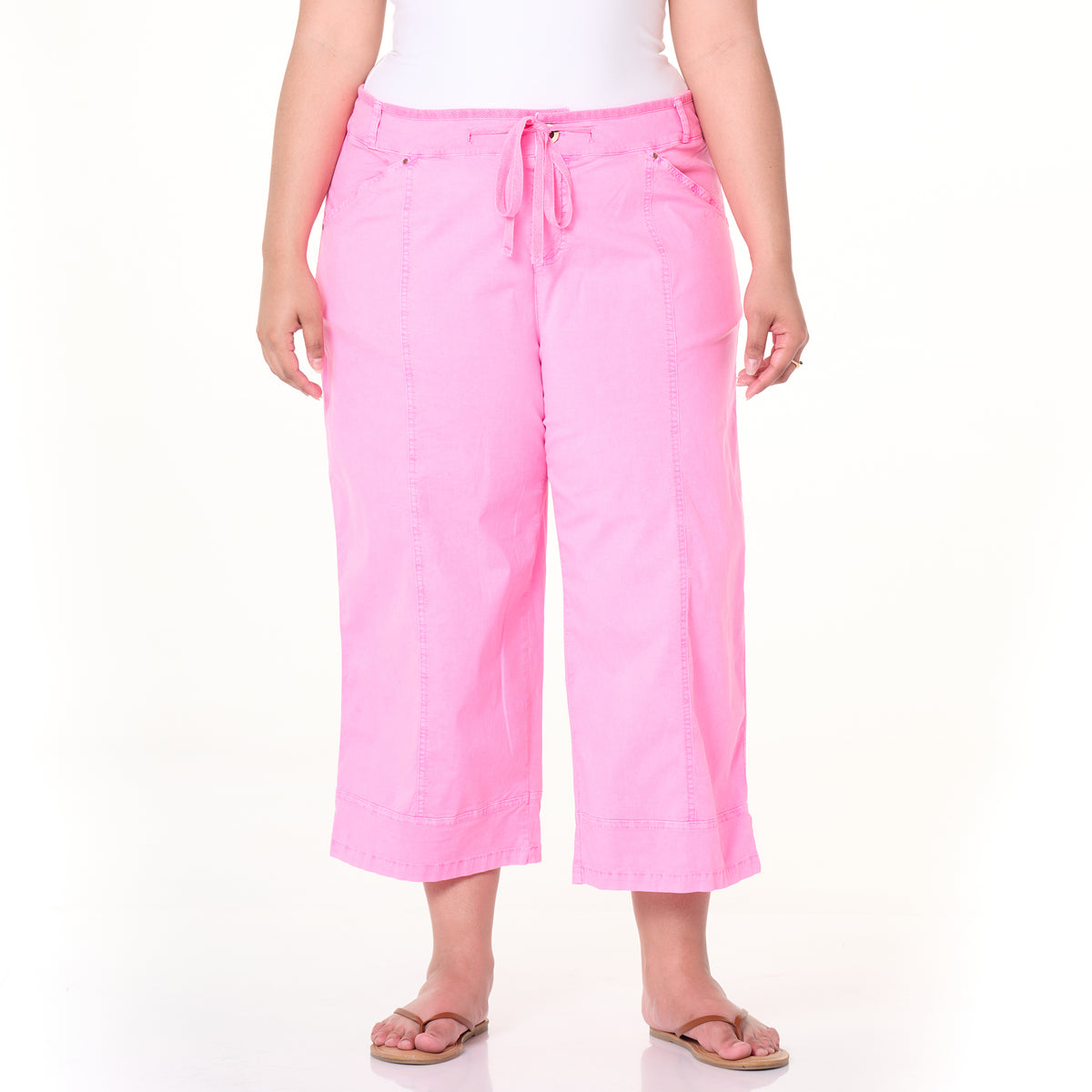 A person is wearing the Fresh Produce Clothes Safari Capris in light pink, styled with flip-flops and a white top. The photo is taken against a plain white background. This plus-size item is available on clearance.