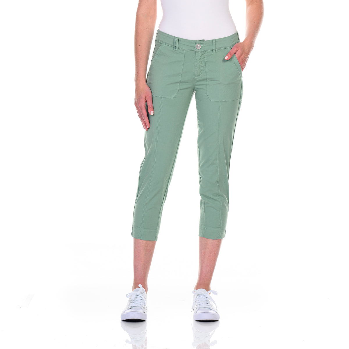 A person wearing Lagoon Safari Pocket Capris by Fresh Produce Clothes, crafted from stretch broadcloth, stands against a white background with one hand in a pocket of the capris and white sneakers completing the look.
