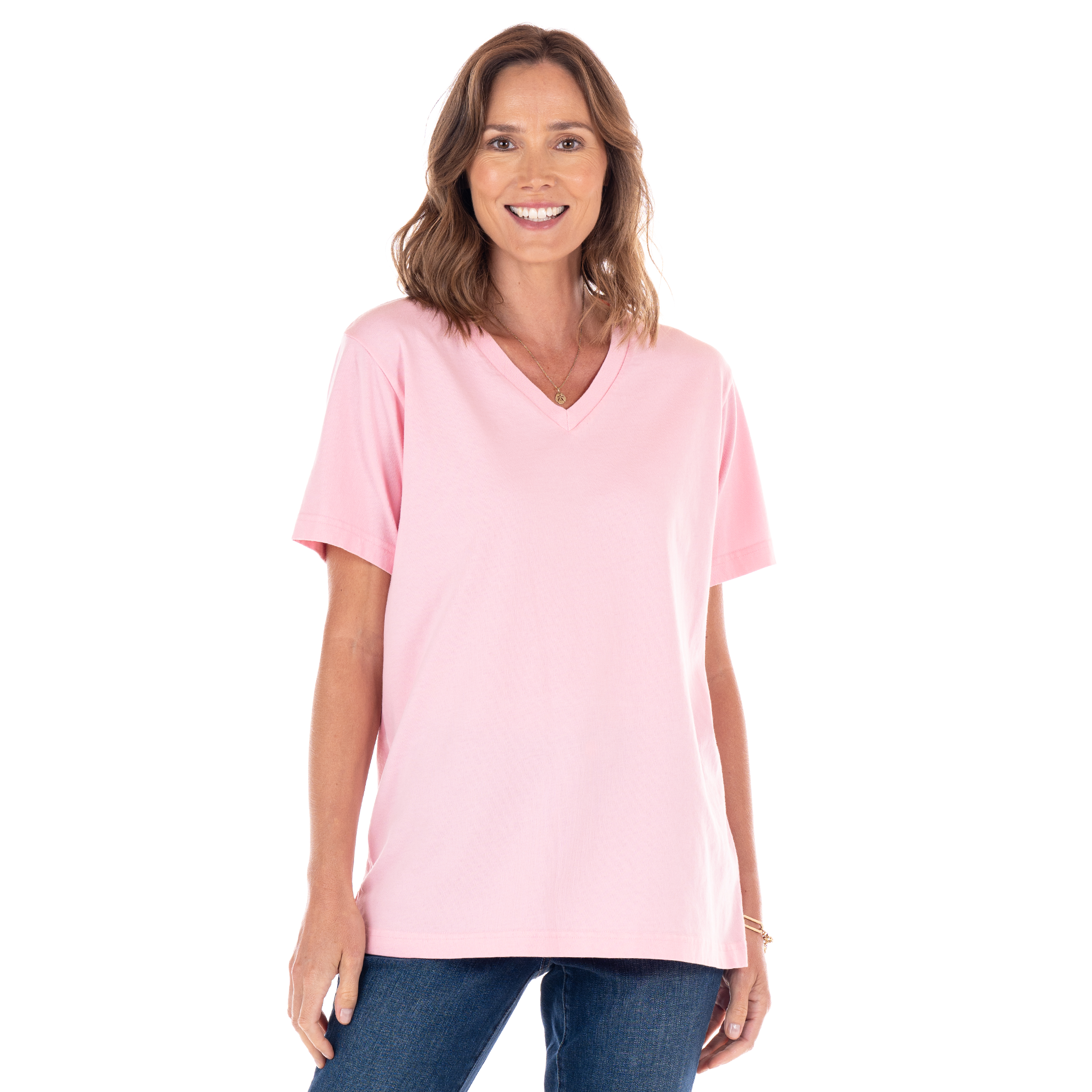 A woman with shoulder-length brown hair wears the Fresh Produce Clothes V-Neck T Blush made in the USA and blue jeans, standing and smiling against a plain white background.